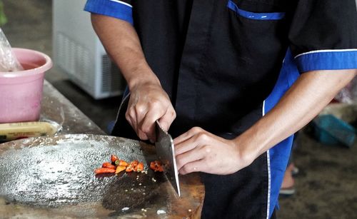 Midsection of man cutting pepper in his kitchen