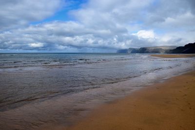 Scenic view of beach against cloudy sky