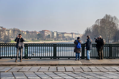 People standing by railing against sky