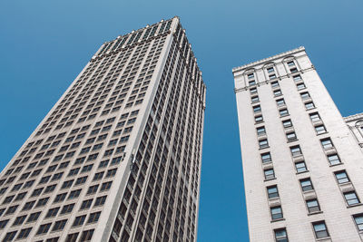 Low angle view of skyscrapers against clear blue sky