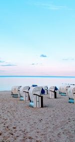 Hooded chairs on beach against sky