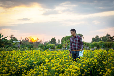 Woman standing on field against yellow flowers