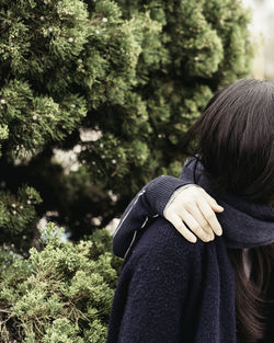 Cropped hand of friend on woman shoulder against tree