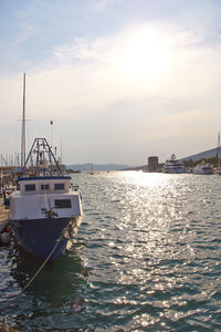 Sailboats moored on sea against sky during sunset