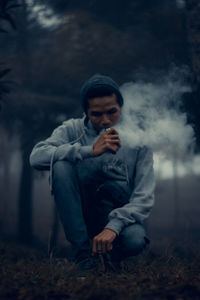 Full length of young man using phone while sitting on land