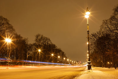 Snow-covered avenue with burning lanterns on a winter evening