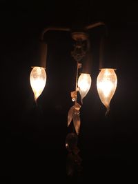 Low angle view of illuminated light bulb against black background