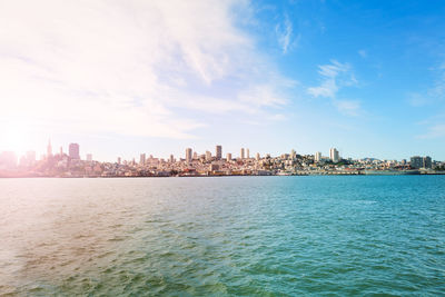 Sea by buildings in city against sky