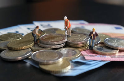 Miniature figurines of worker working on a pile of money