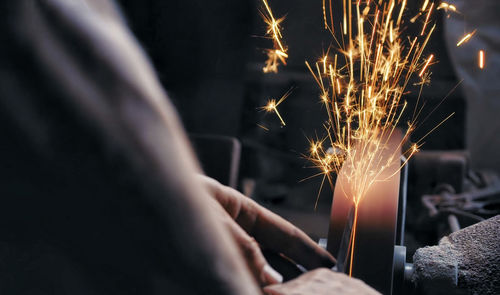 Midsection of woman holding sparkler at night