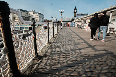 Rear view of people walking on footpath in city