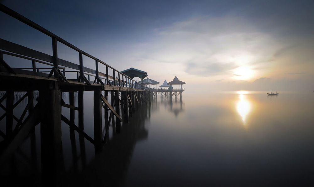 sunset, sky, water, sun, reflection, sea, tranquility, scenics, tranquil scene, beauty in nature, nature, waterfront, cloud - sky, built structure, sunlight, silhouette, horizon over water, idyllic, sunbeam, pier