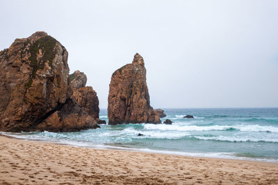 Rock formation on beach against clear sky