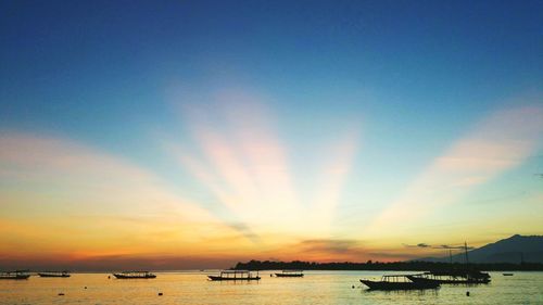 Silhouette boats on sea against sky during sunset