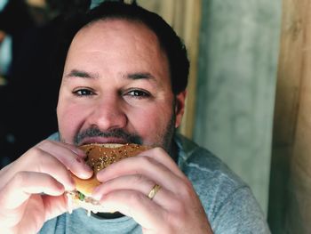 High angle portrait of man eating burger at home