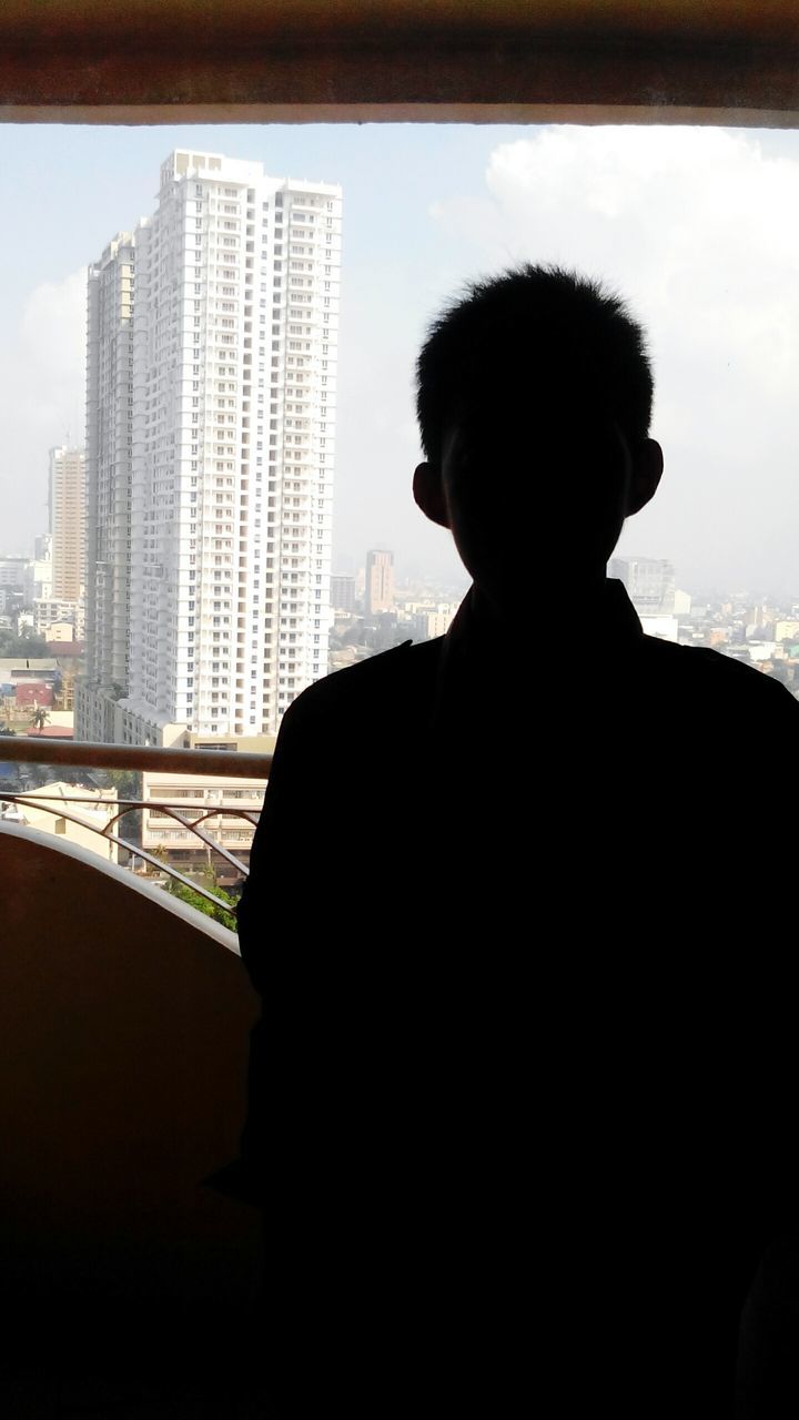 REAR VIEW OF SILHOUETTE MAN SITTING ON OFFICE BUILDING