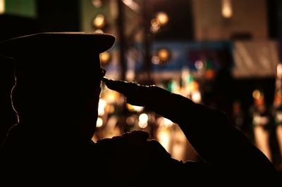 Rear view of silhouette man saluting in city at night