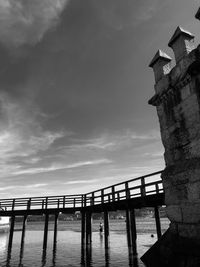 Low angle view of bridge over sea against buildings