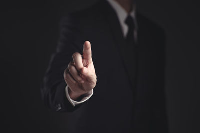 Midsection of man making face against black background