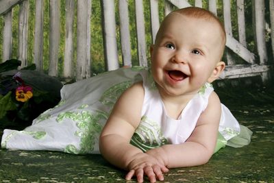 Close-up of cheerful baby girl lying on floor