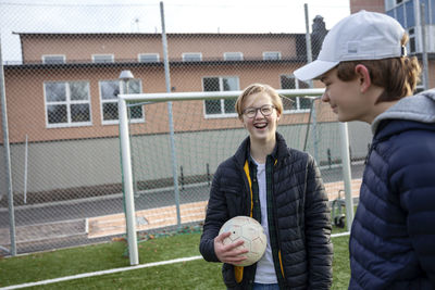 Smiling friends standing on school soccer field