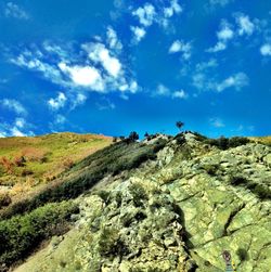 Low angle view of green landscape against blue sky