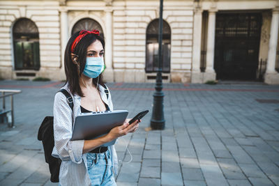 Full length of woman using phone on street