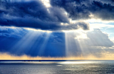 Sunlight streaming through clouds over sea