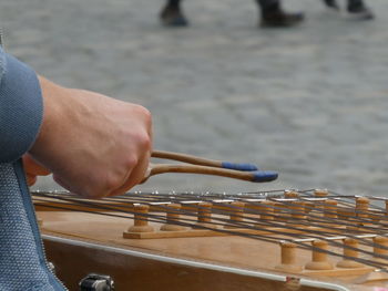 Cropped hands of person playing musical instrument on street in city