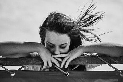 Close-up portrait of woman with arms raised against sky