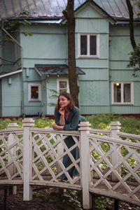 Side view of young woman standing by house