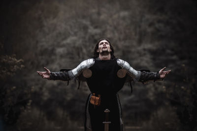 Young man wearing costume while standing against trees