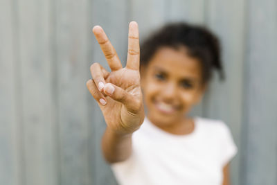 Close-up of girl showing peace sign