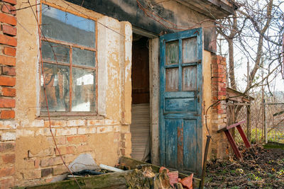 Retro-styled abandoned brick barn or farmhouse with open blue doors and big window .