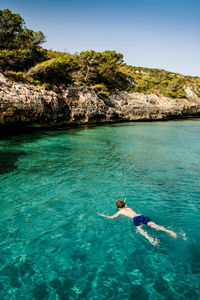 High angle view of shirtless man swimming in sea