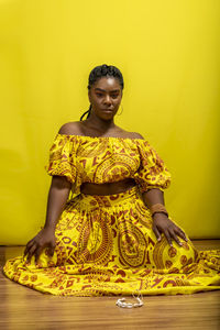 Young woman wearing colorful long clothes over yellow background. natural expression.