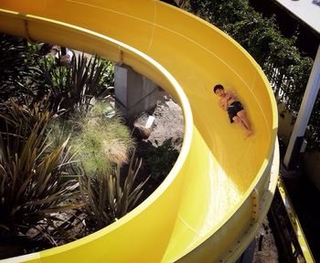 Full length of happy boy on yellow water slide