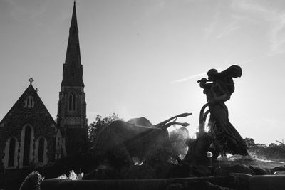 Statue against temple and building against sky