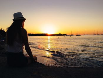 Silhouette woman standing on beach against sky during sunset