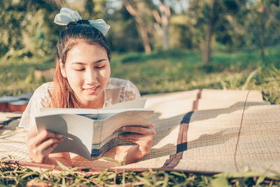 Young woman reading book outdoors