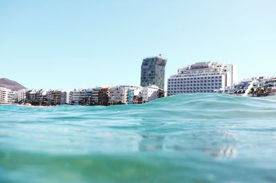 Swimming pool in city against clear blue sky