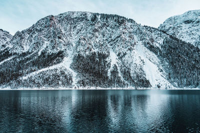 Scenic view of lake by snowcapped mountains against sky