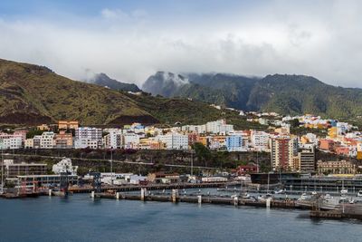 Buildings in town by mountains against sky