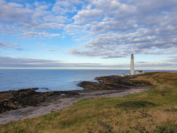 Lighthouse by sea against sky