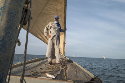 Man standing on boat in sea against sky