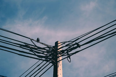 Low angle view of silhouette electricity pylon against sky during sunset