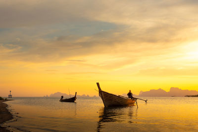 Fishing boat in sea against sky during sunset