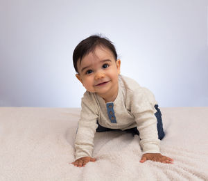 Portrait of smiling boy sitting on bed at home