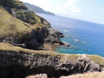 Scenic view of sea by cliff against sky