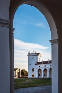 Buildings against sky seen through arch window